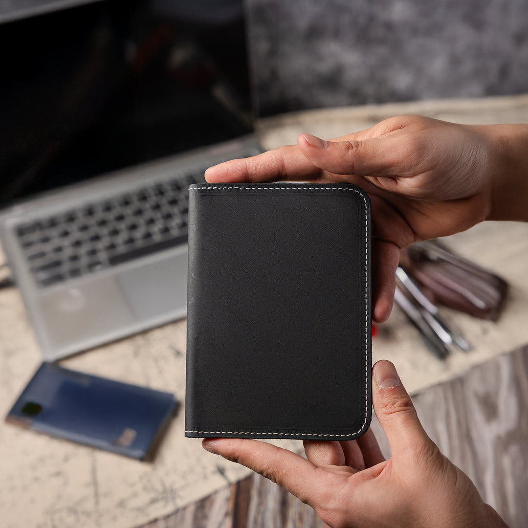 Person holding a black leather wallet with a blurred office background