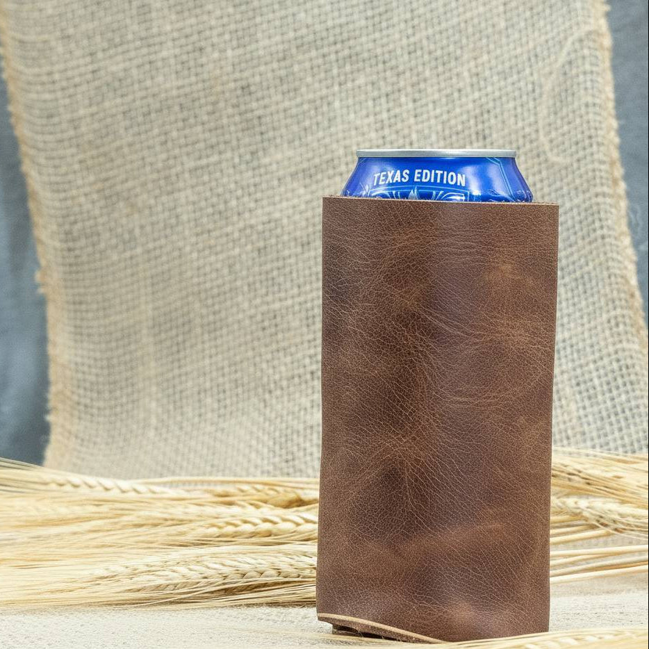 Brown leather can holder with a blue can inside, placed on a textured surface.