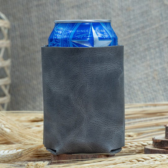 Blue can in a black leather can cooler on a textured surface